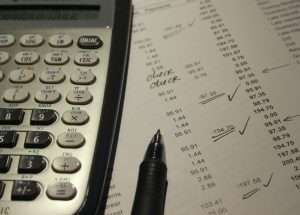 Calculadora e anotações financeiras ilustrando a importância da gestão financeira para licitantes no controle dos indicadores financeiros.