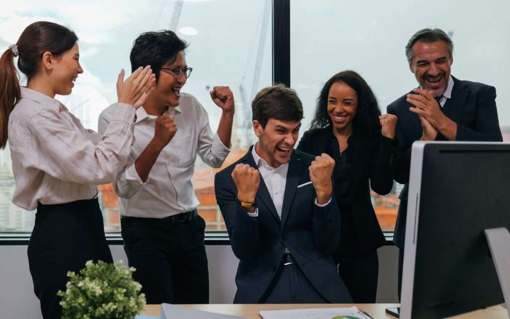 Time corporativo comemorando vitória ao aplicar estratégias de como ganhar licitação com sucesso.