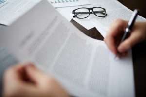 Pessoa analisando documentos e tomando notas, simbolizando como ler um edital de licitação com atenção aos prazos, exigências e critérios.