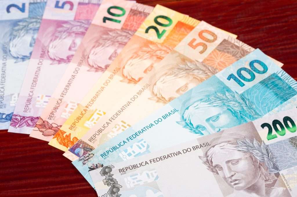Notas de Real sobre uma mesa, representando a gestão financeira para licitantes na definição da margem de lucro ideal.