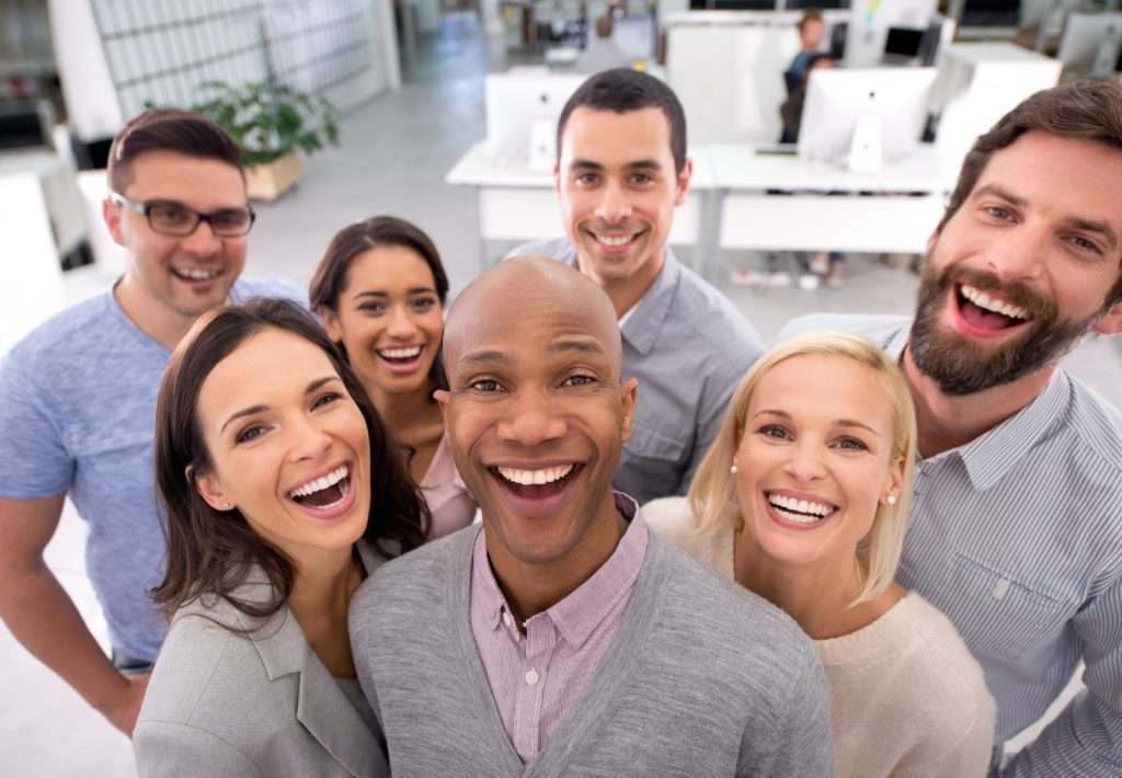 Equipe feliz e engajada no escritório, representando estratégias eficazes de como aumentar a produtividade da empresa por meio do bem-estar e da motivação dos colaboradores.