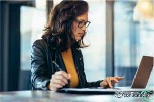 mulher conferindo informações sobre Fase interna da licitação no computador.