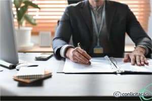 Profissional conferindo documentos em uma mesa de escritório. Imagem ilustrativa para texto reajuste e repactuação de preços.