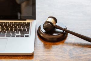 lateral de um notebook com um malhete ao lado e um pregão em andamento