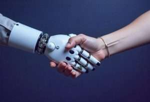 Uma mão humana e robótica se apertando. Este é o futuro das licitações: colaboração entre IA e humanos.
