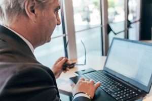 Homem maduro de terno analisando informações em um laptop, representando a gestão estratégica e a transparência proporcionadas pelo Portal Nacional de Contratações Públicas (PNCP) nas contratações públicas no Brasil.